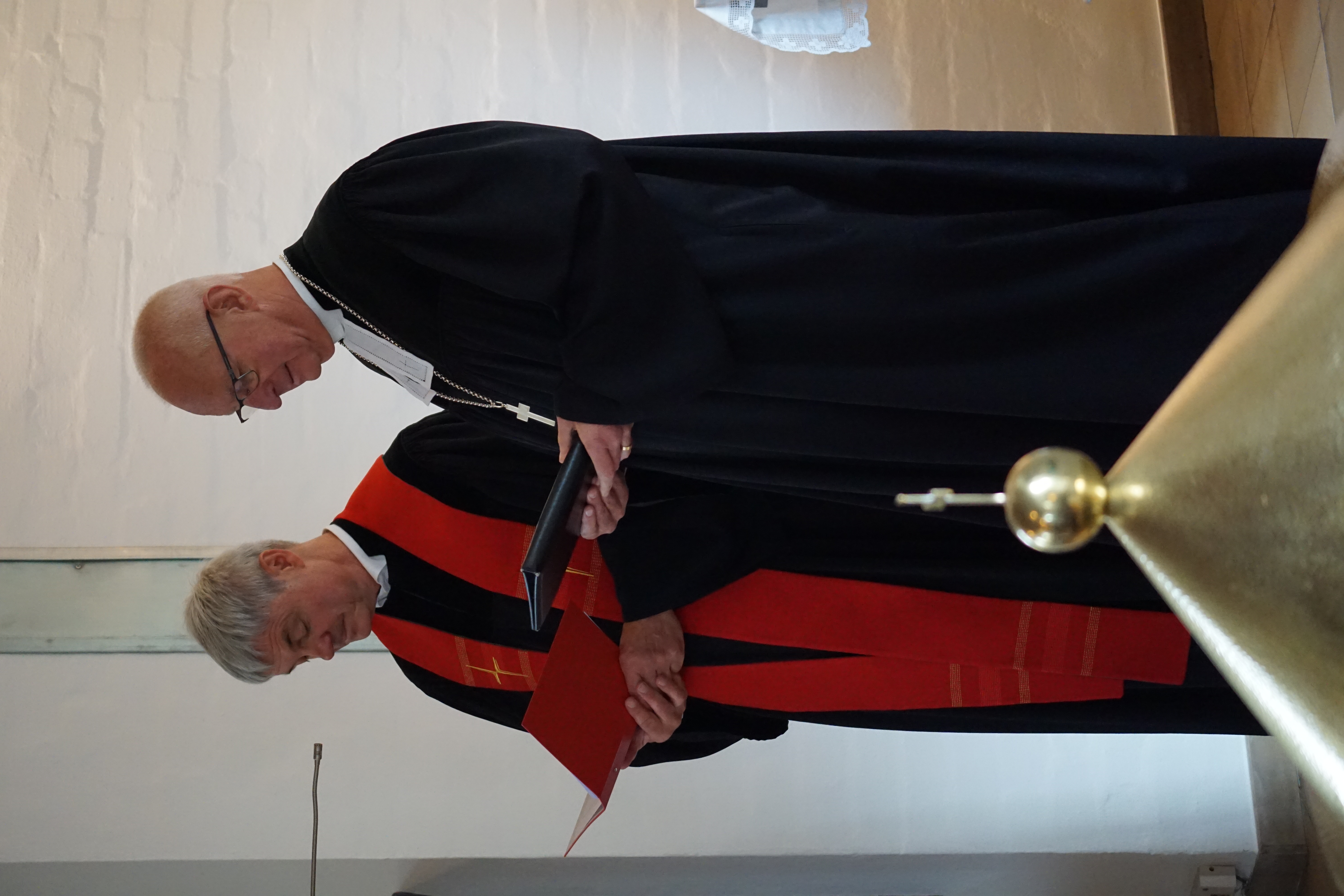 Regionalbischof und Pfarrer vor dem Altar.